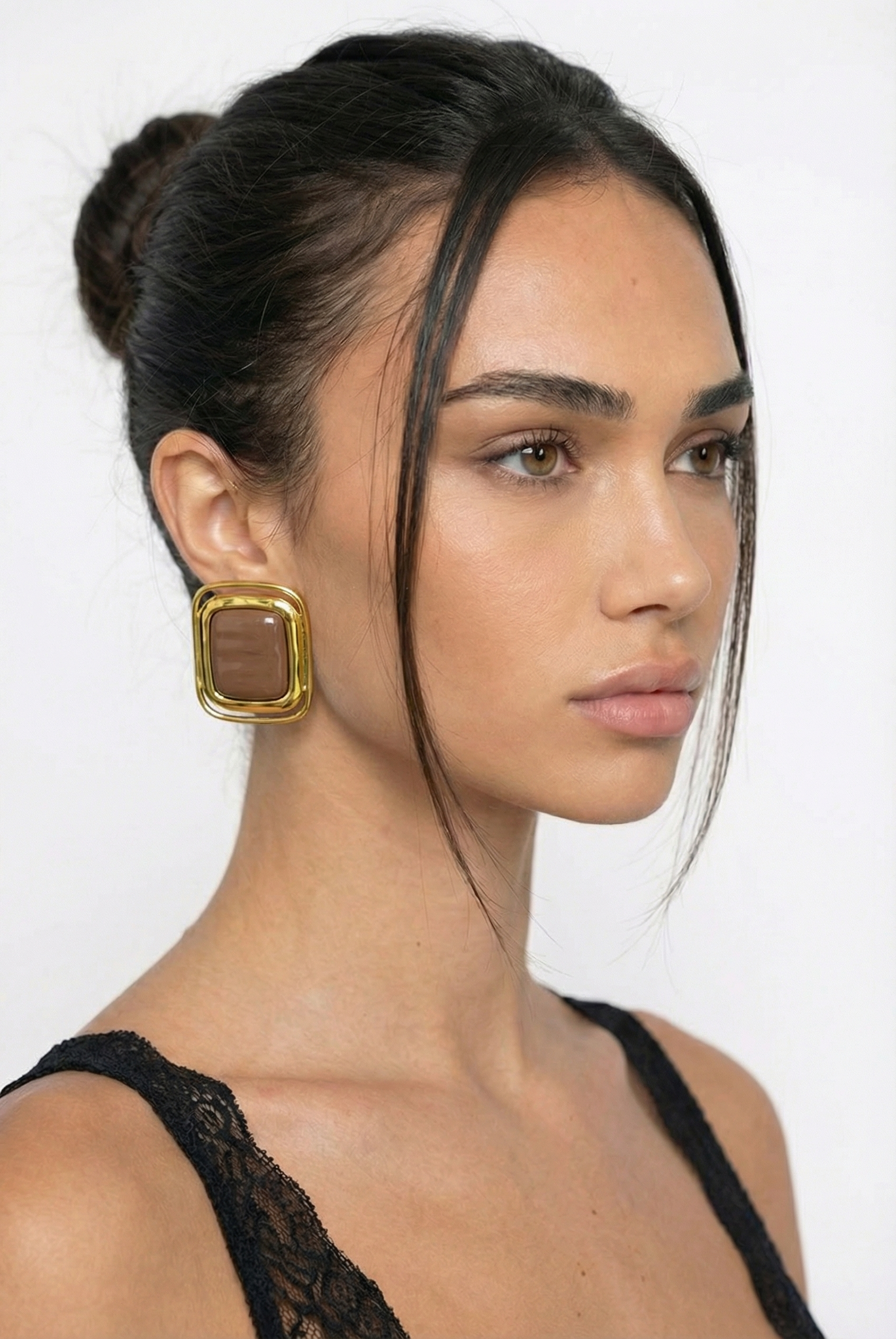 Woman wearing a gold earring with a plain background