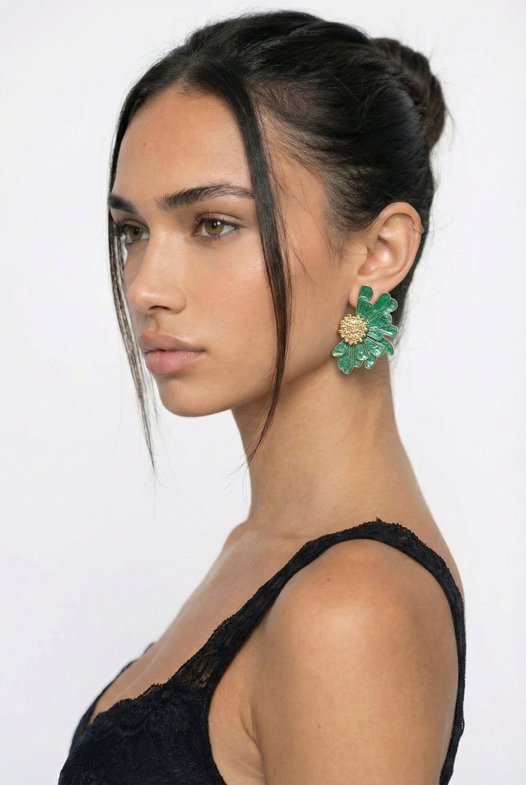 Woman wearing green earrings with a plain background