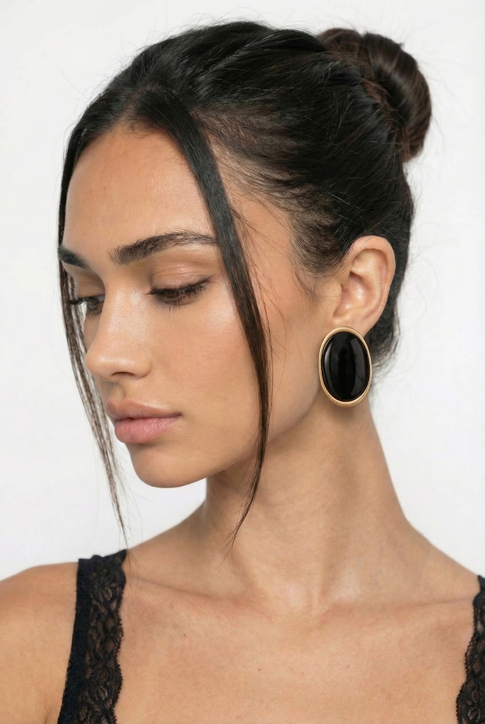 Woman wearing large black earrings with a plain background