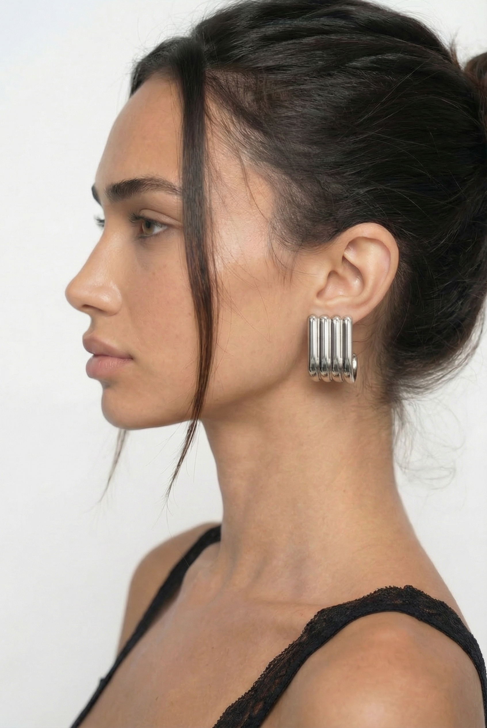 Woman wearing a silver earring with a plain background