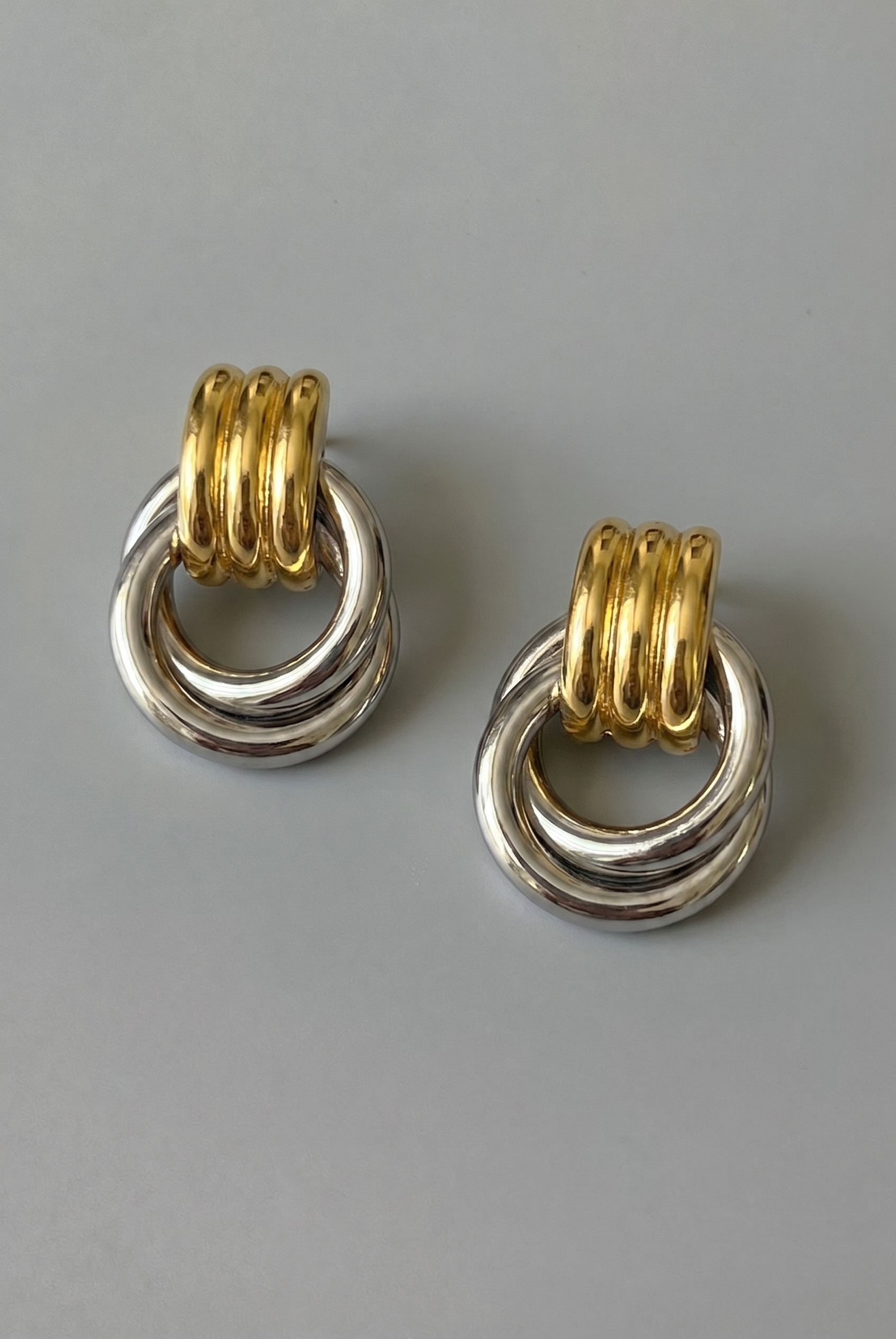 Pair of earrings with gold and silver rings on a gray background