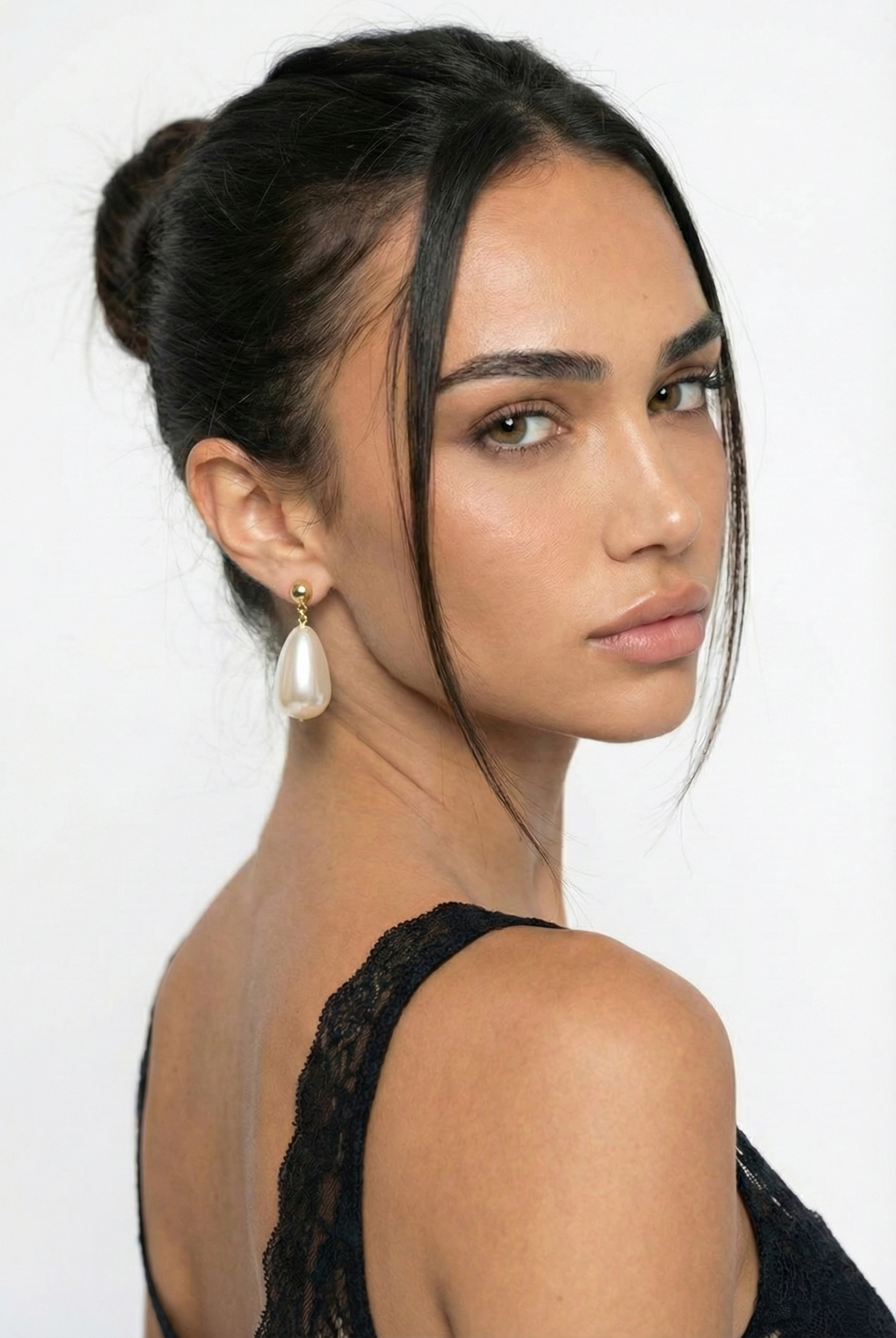 Woman with styled hair and earrings against a white background