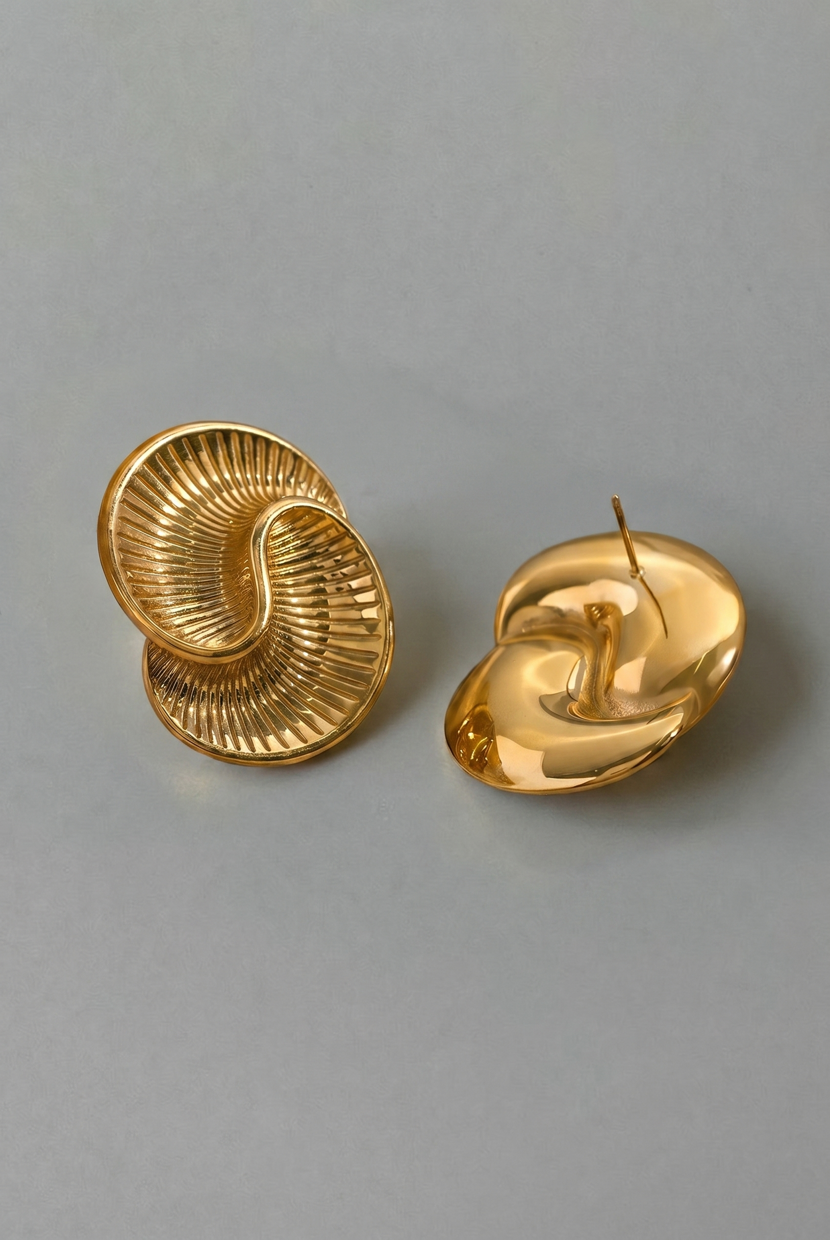 Pair of gold spiral earrings on a gray background