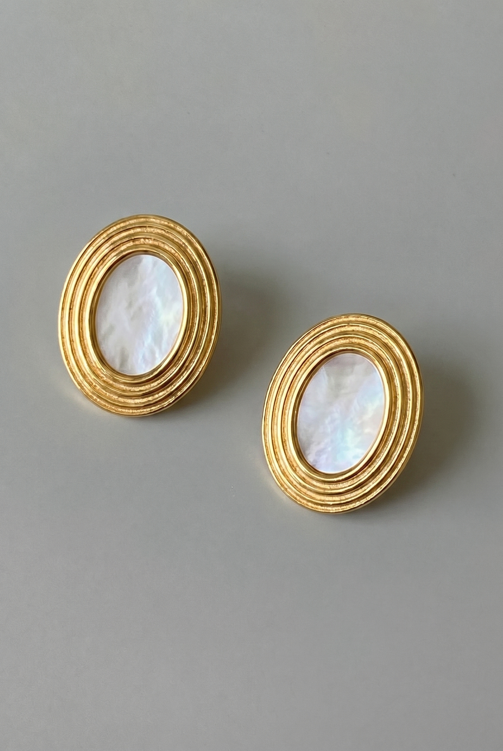 Pair of gold earrings with circular designs on a gray background