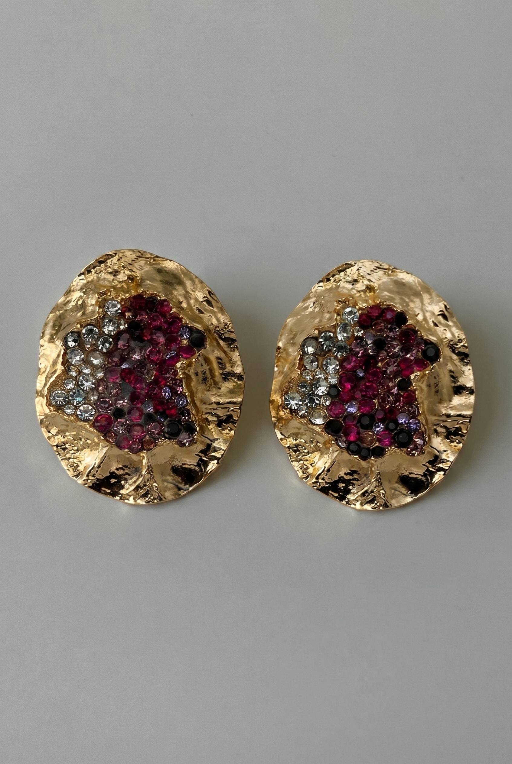 Gold earrings with gemstone accents on a gray background