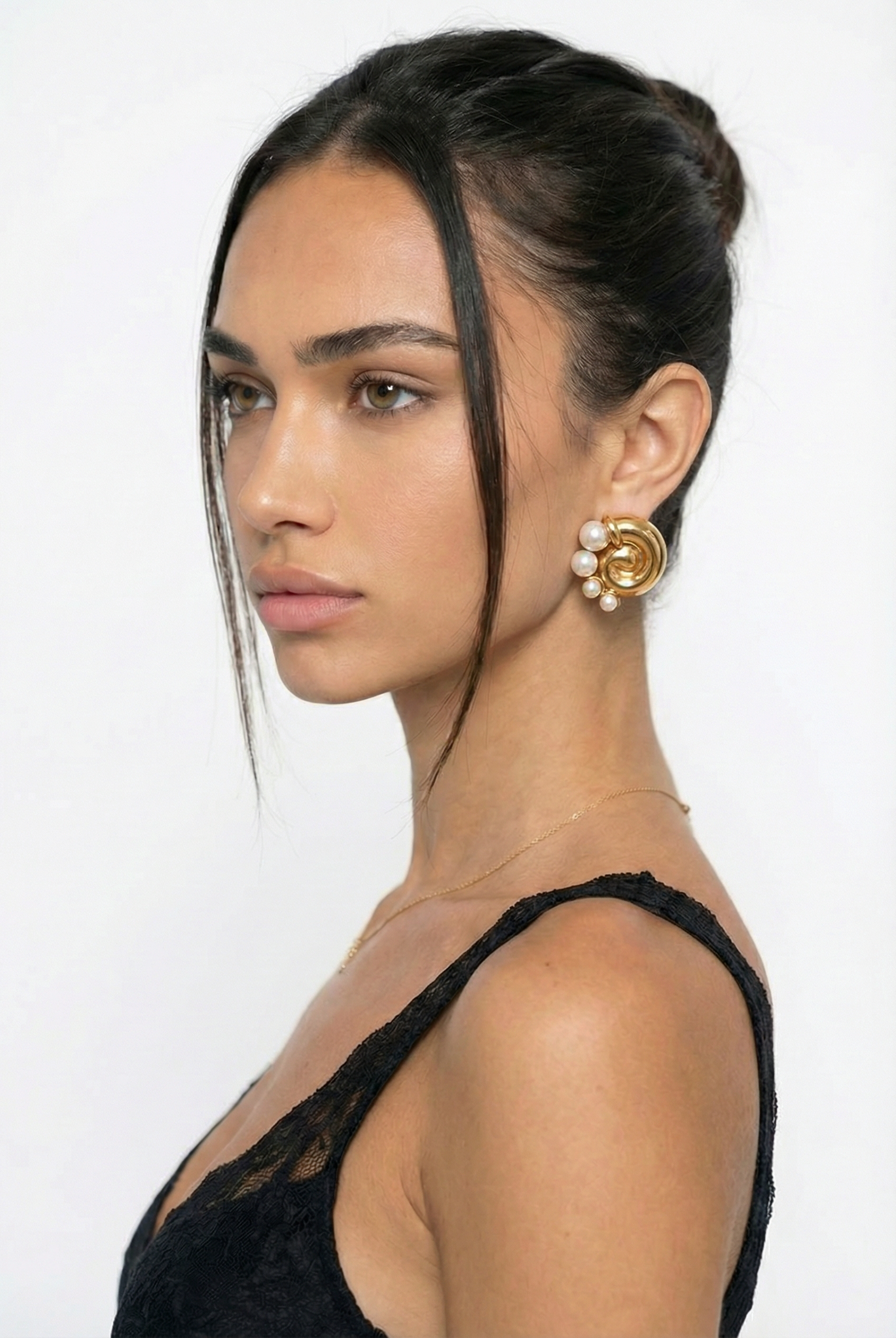 Woman wearing gold earrings with a plain background