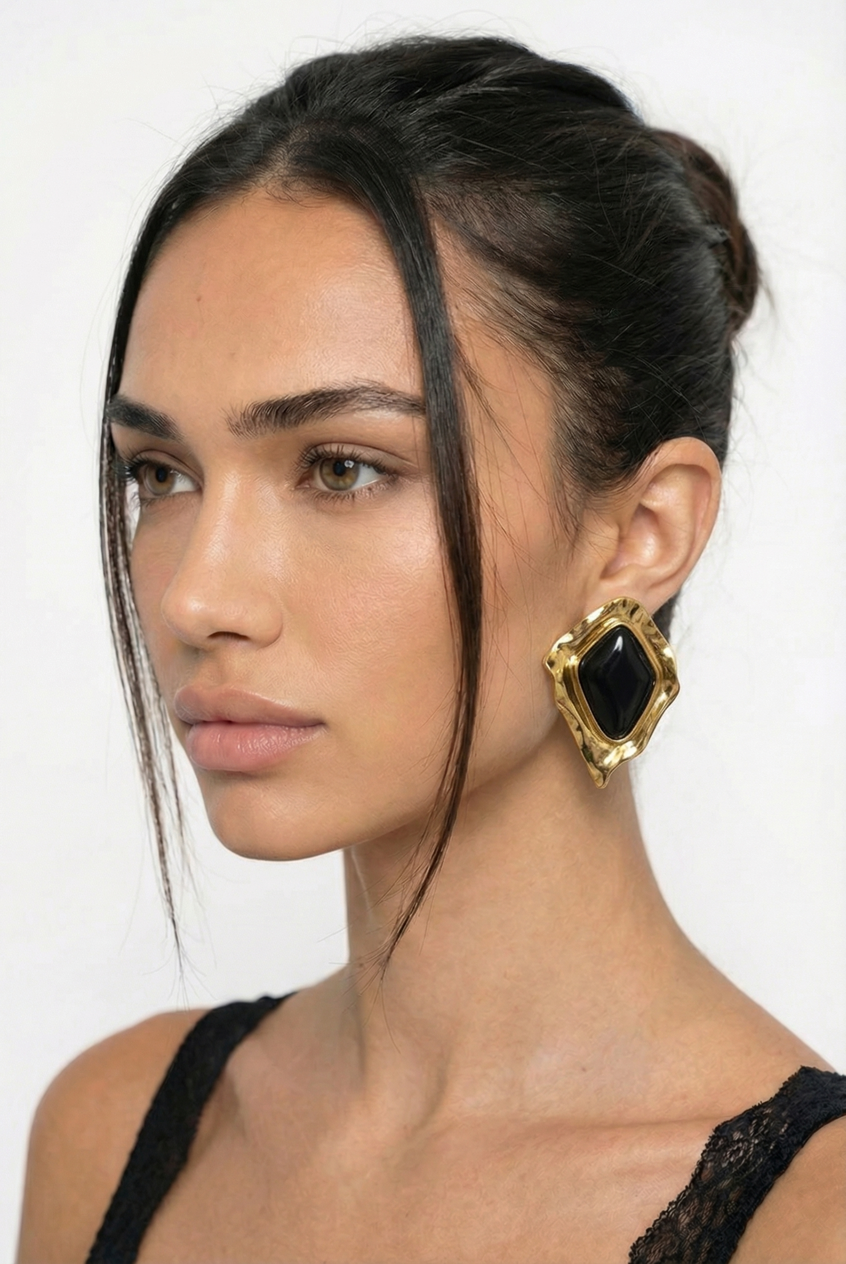 Woman wearing a gold and black earring on a white background
