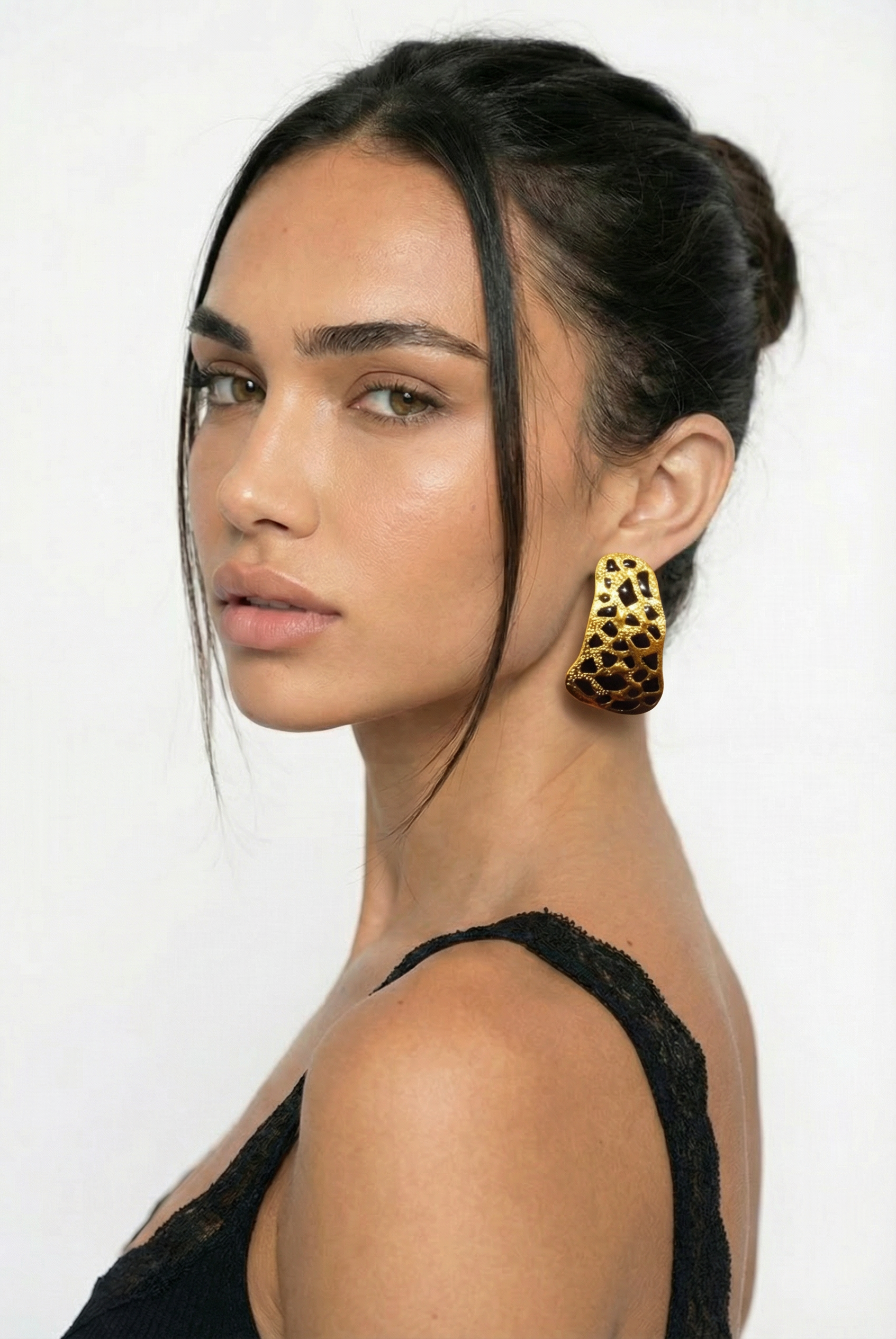 Woman wearing a black top and leopard print earrings on a white background