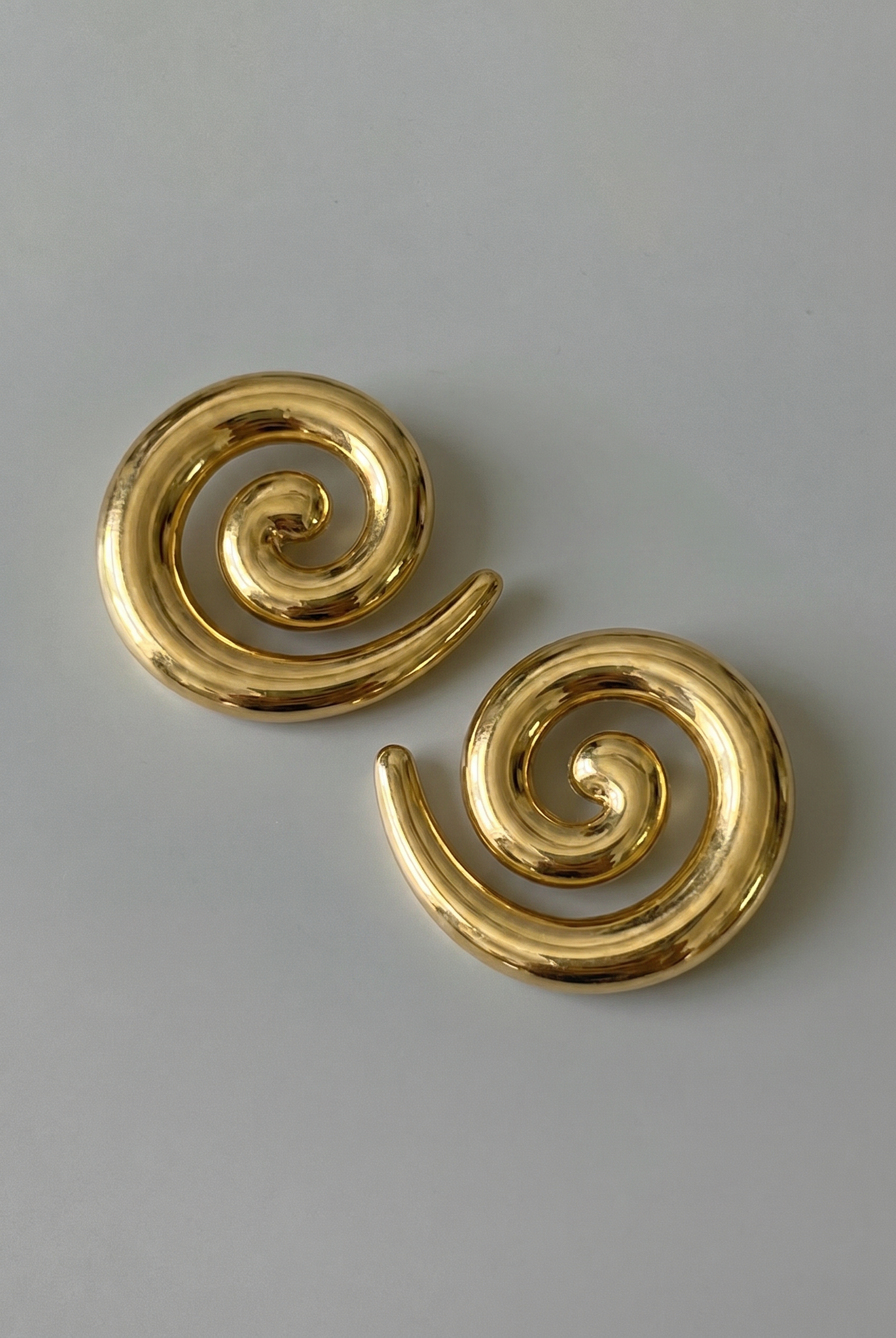 Pair of gold spiral earrings on a gray background
