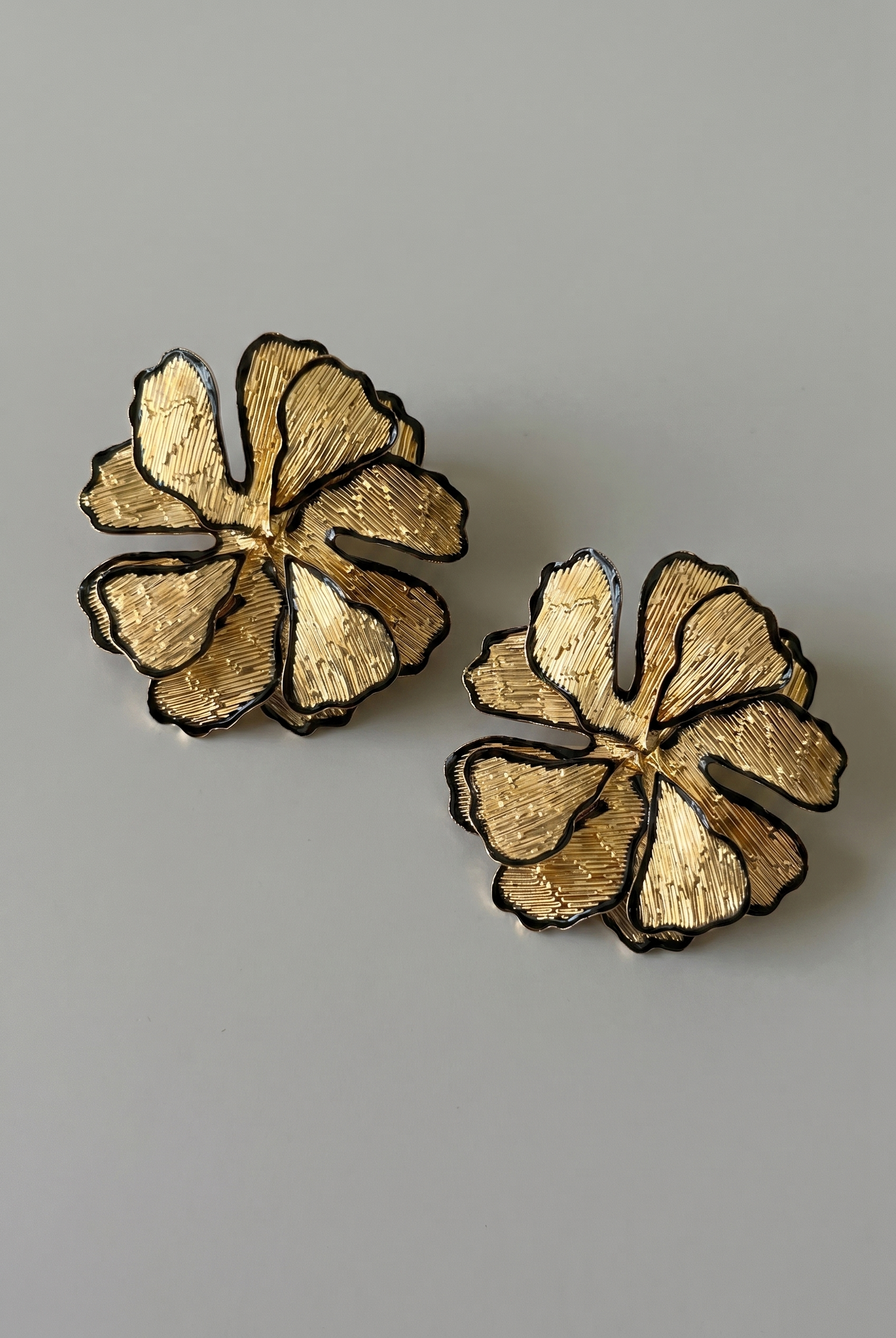 Pair of gold floral earrings on a gray background