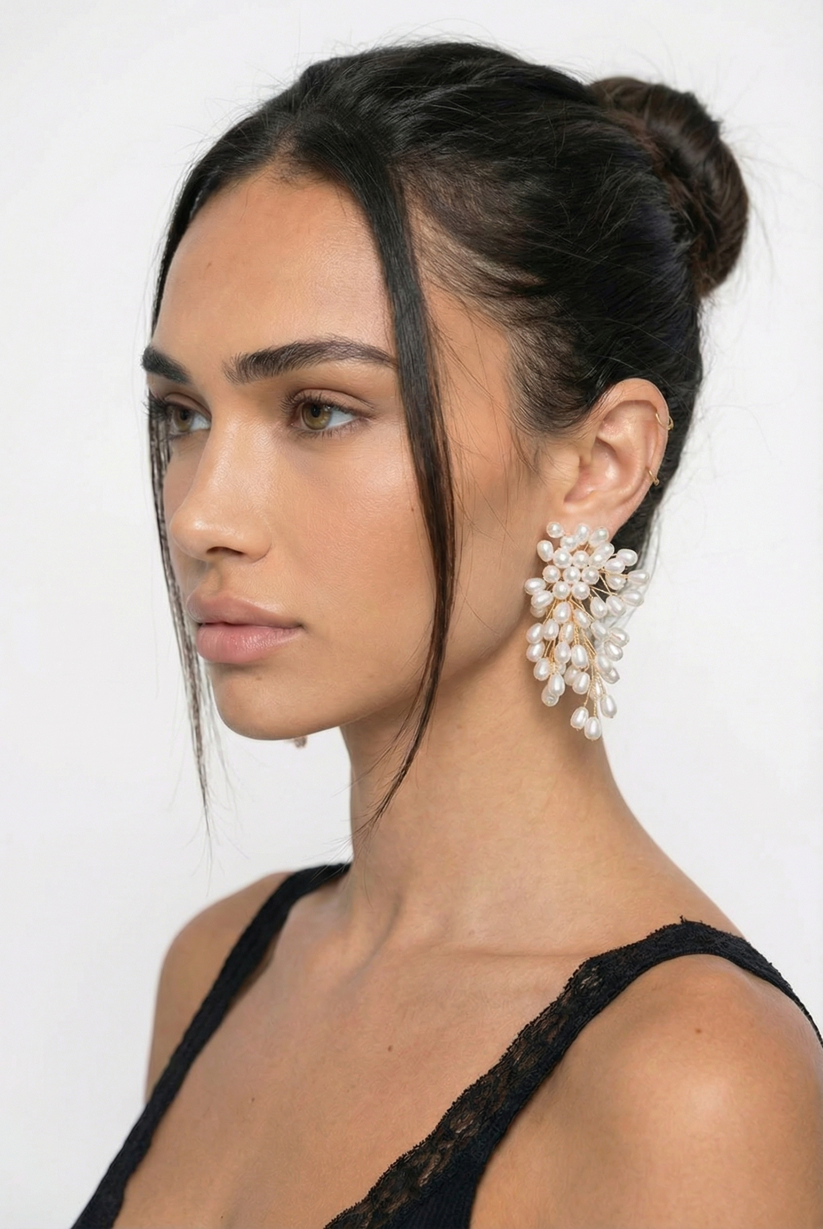 Woman wearing pearl earrings with a neutral background
