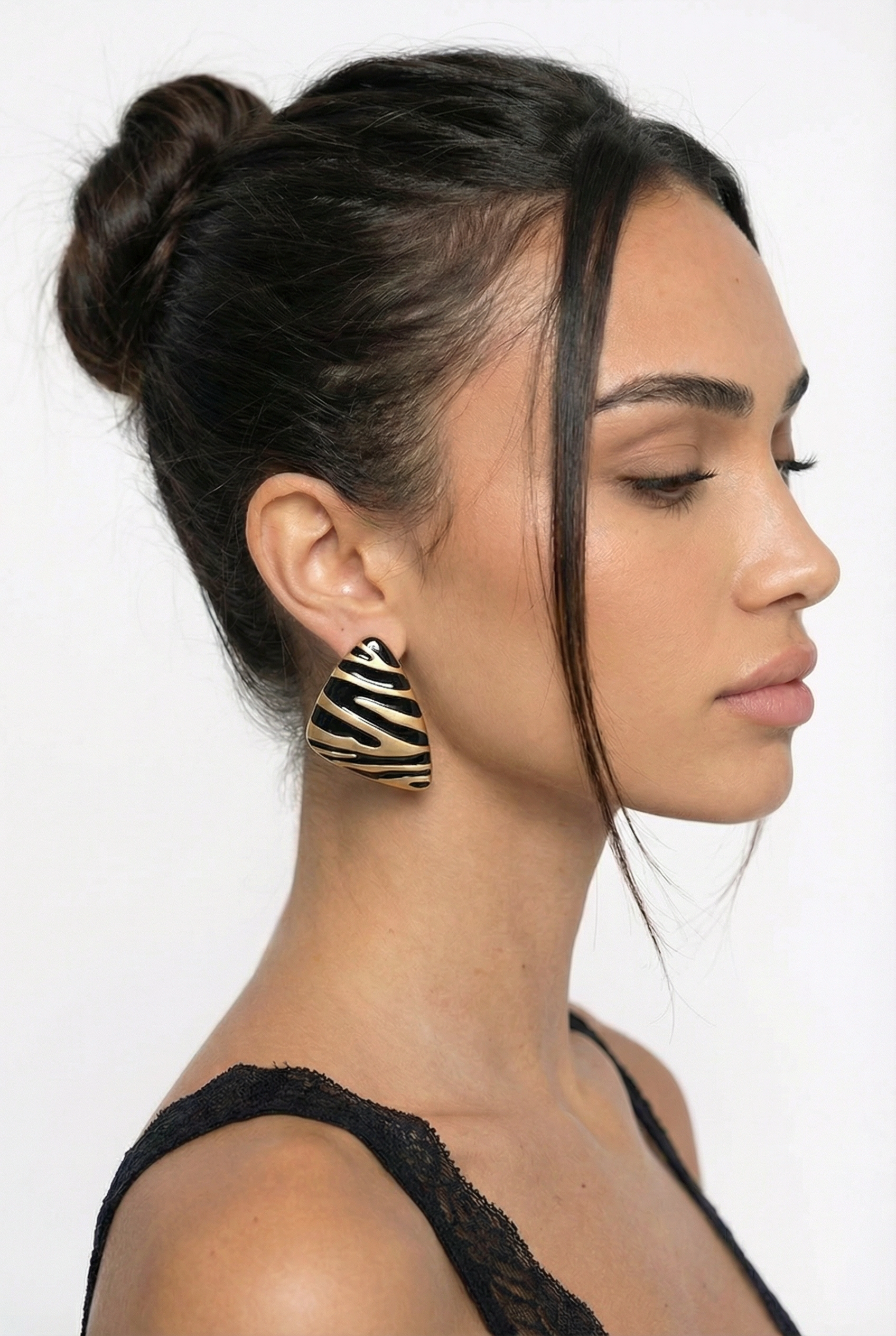 Woman with styled hair and zebra-patterned earrings on a white background