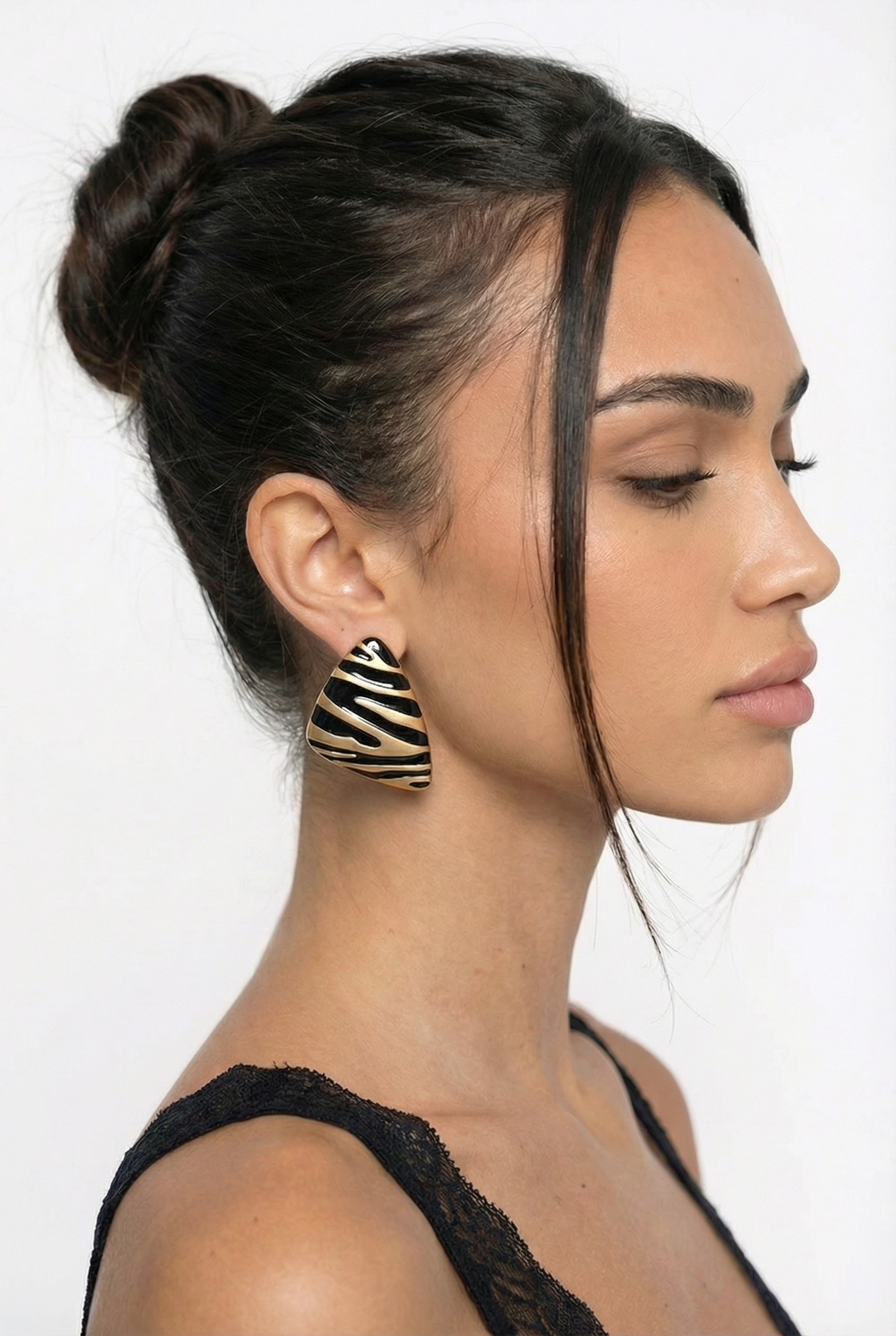 Woman with styled hair and zebra-patterned earrings on a white background