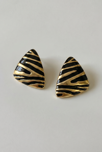 Pair of gold and black striped earrings on a light gray background