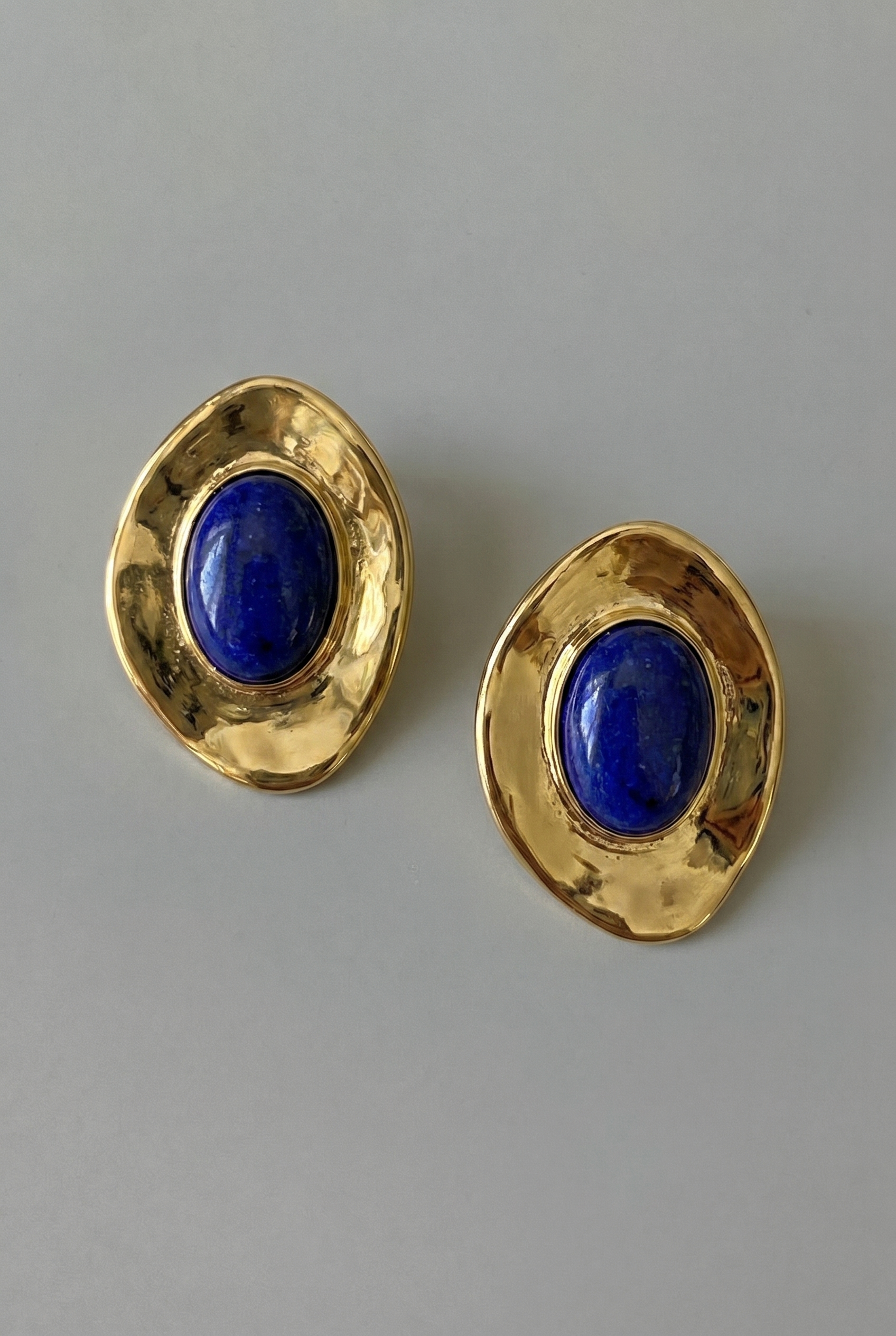 Gold earrings with blue stones on a gray background