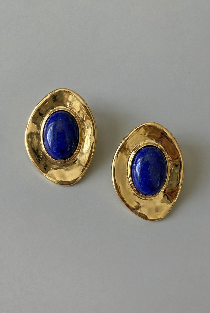 Gold earrings with blue stones on a gray background