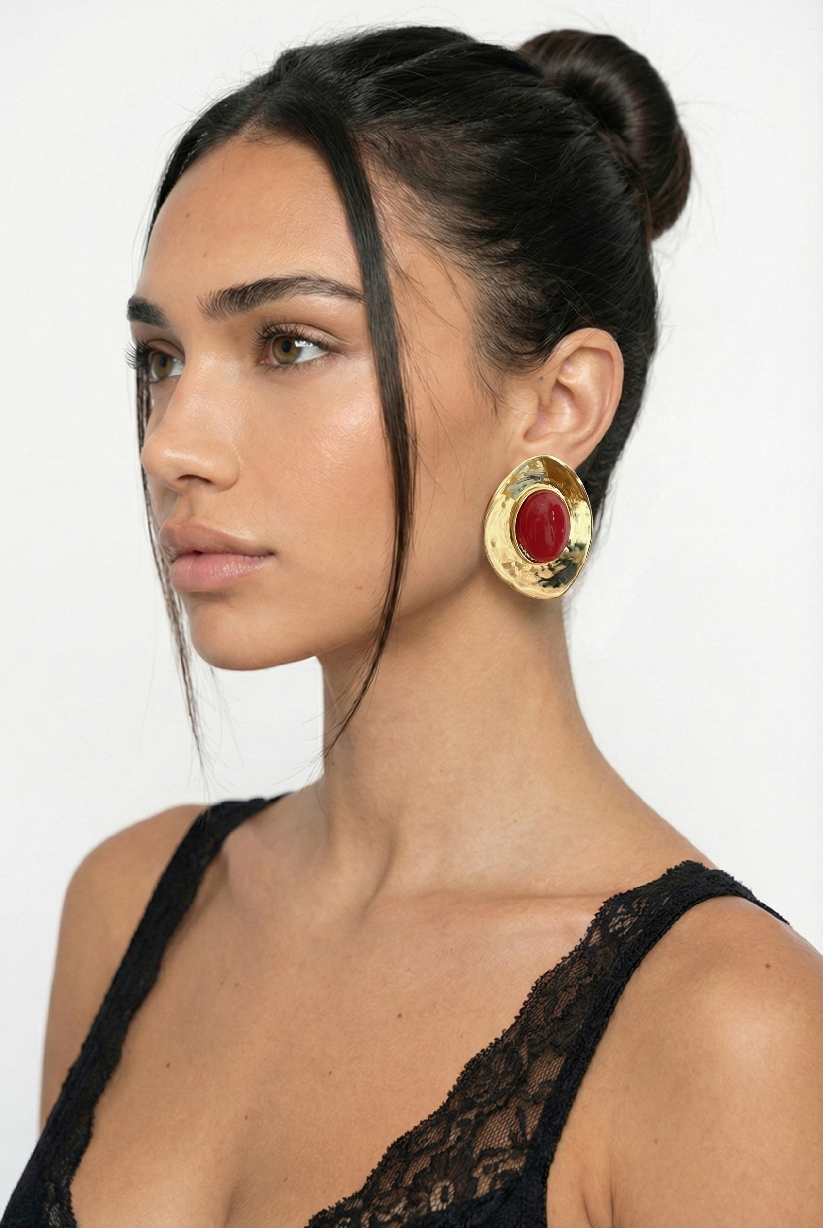 Woman wearing gold hoop earrings with a plain background