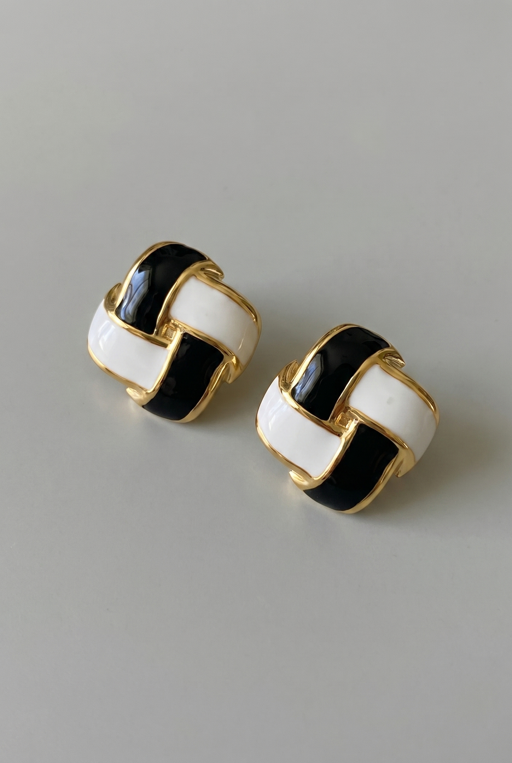 Pair of earrings with black and white circular design on a gray background
