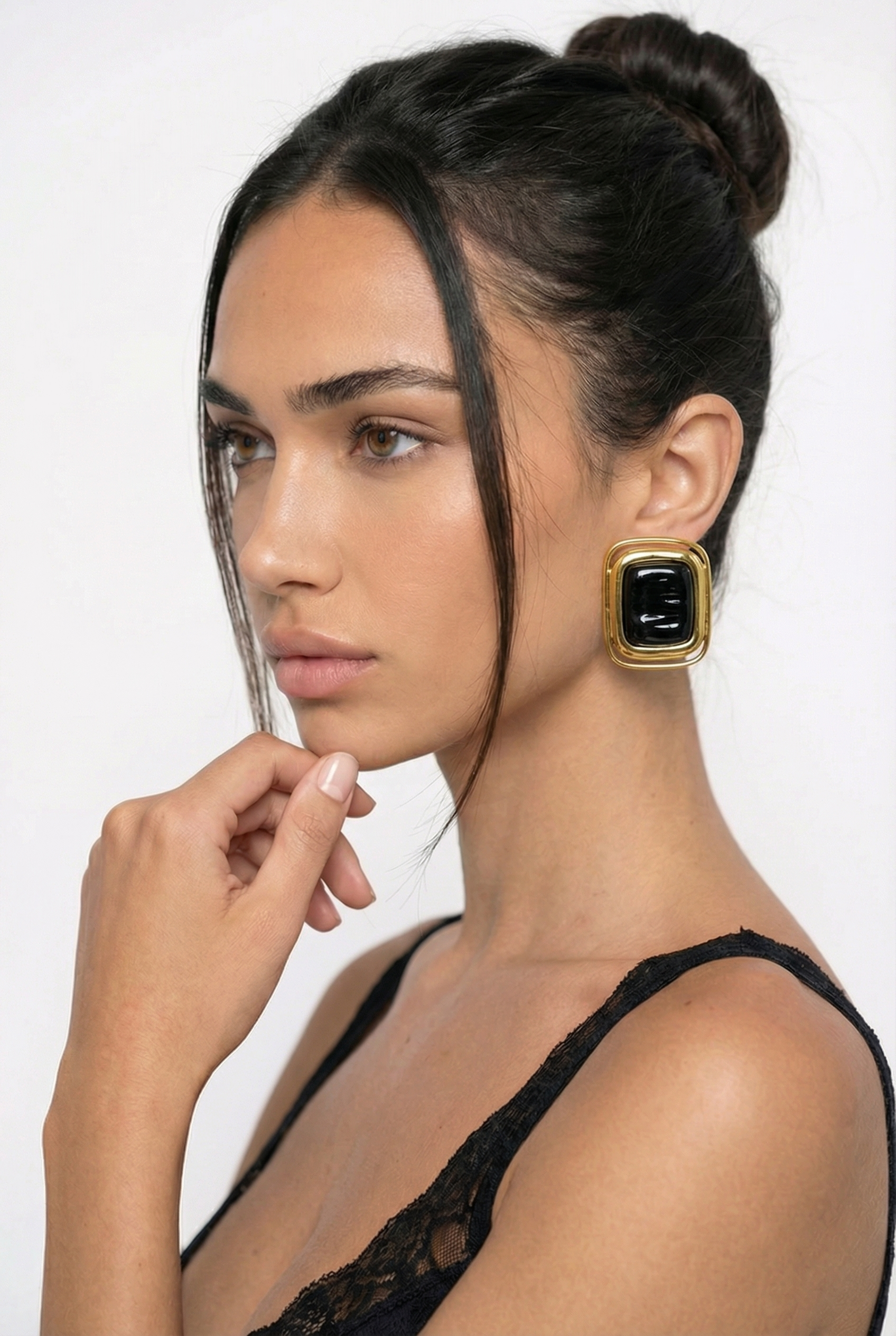 Woman wearing a black dress and gold earrings with a white background