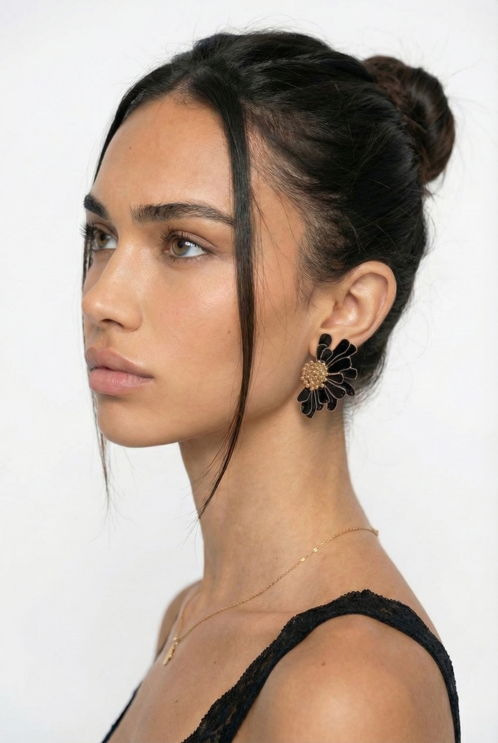 Woman wearing a black floral earring on a white background