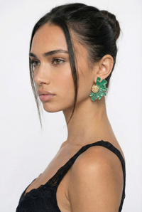 Woman wearing green earrings with a plain background