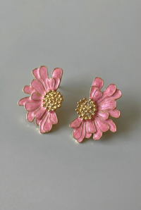Pink flower-shaped earrings with gold centers on a gray background