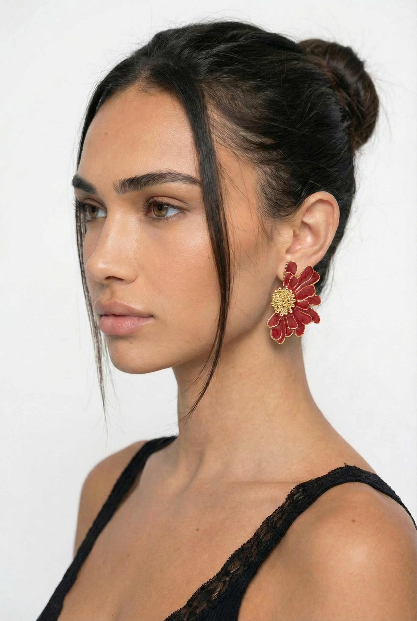 Woman wearing a red floral earring against a white background