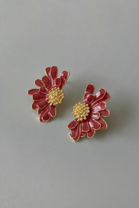 Pair of red floral earrings with gold centers on a gray background