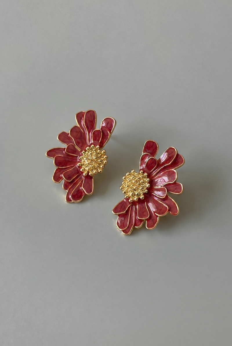 Pair of red floral earrings with gold centers on a gray background