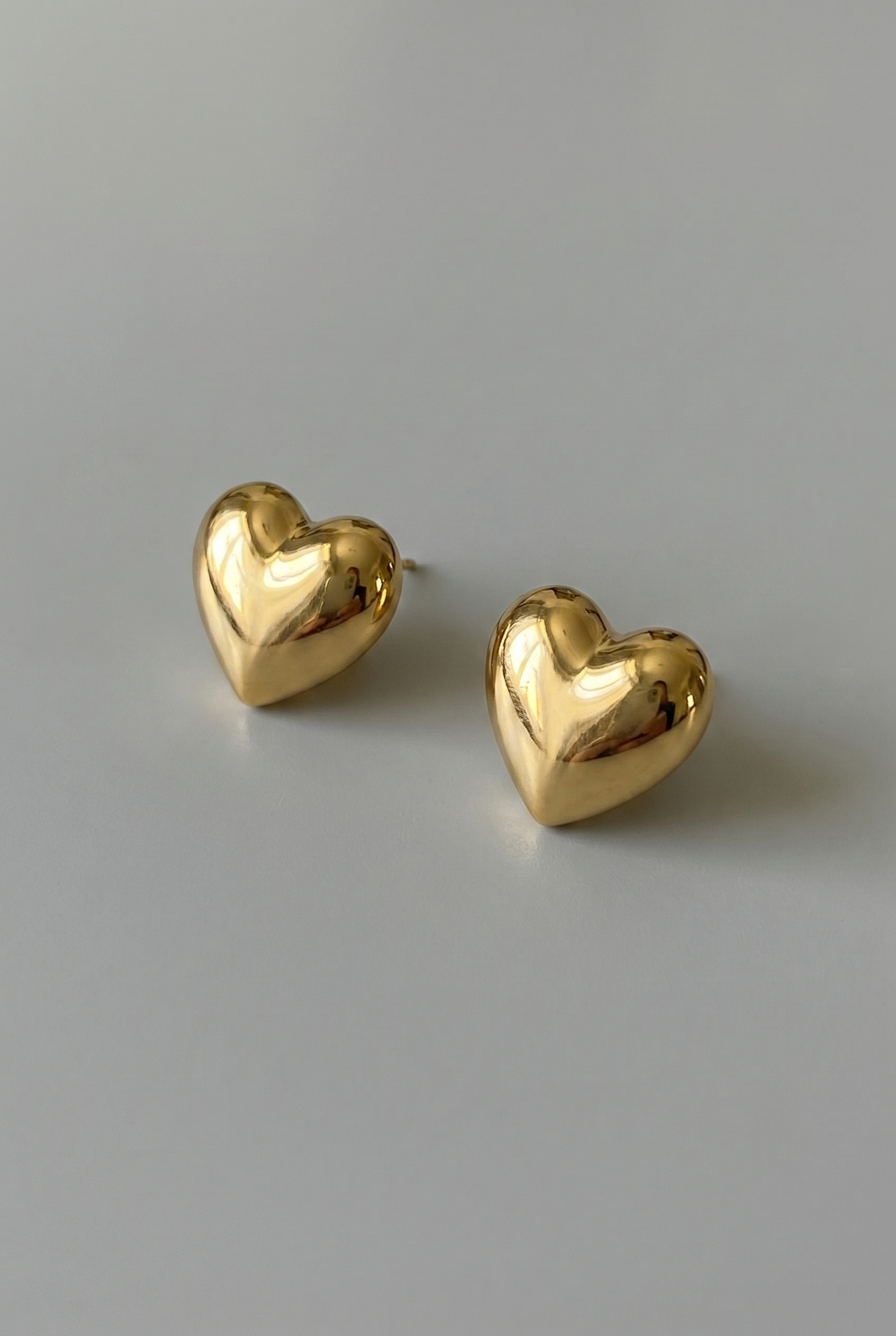 Gold heart-shaped earrings on a gray background