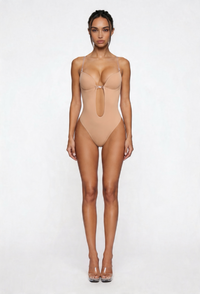 Woman wearing a beige shapewear bodysuit on a white background