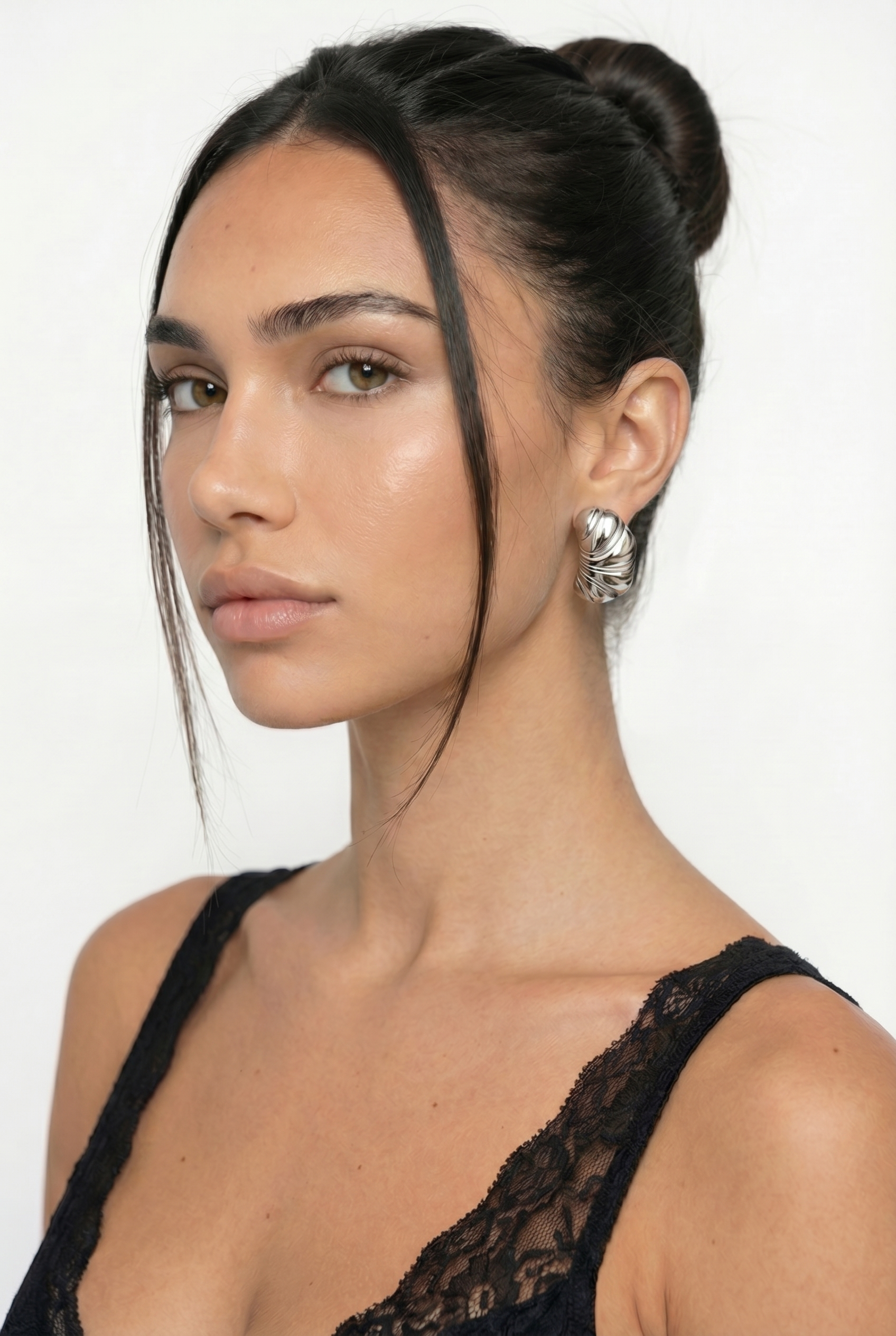 Woman with styled hair and black lace top against a white background