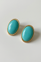 Turquoise earrings with gold frames on a light gray background