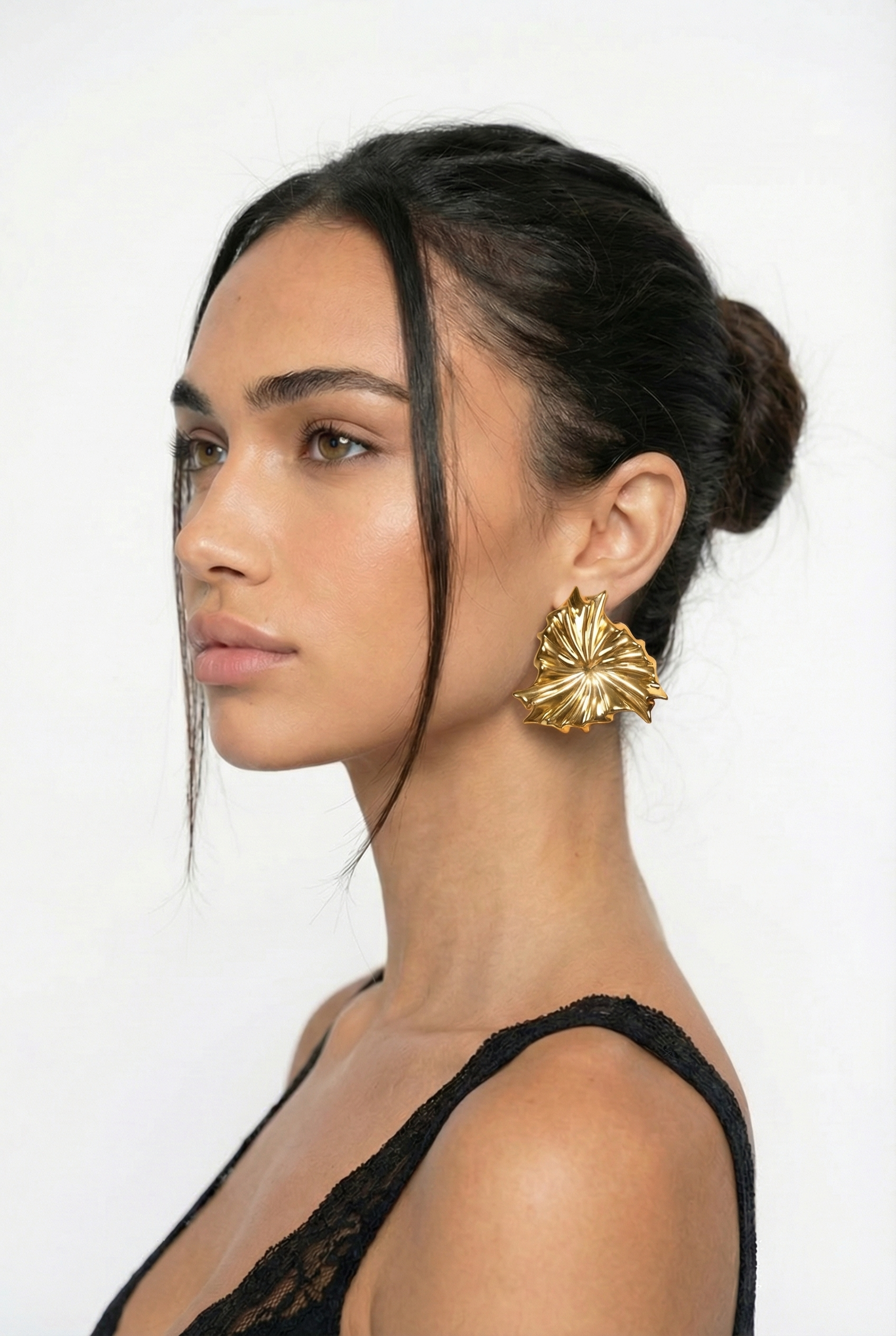 Woman wearing gold earrings with a plain background