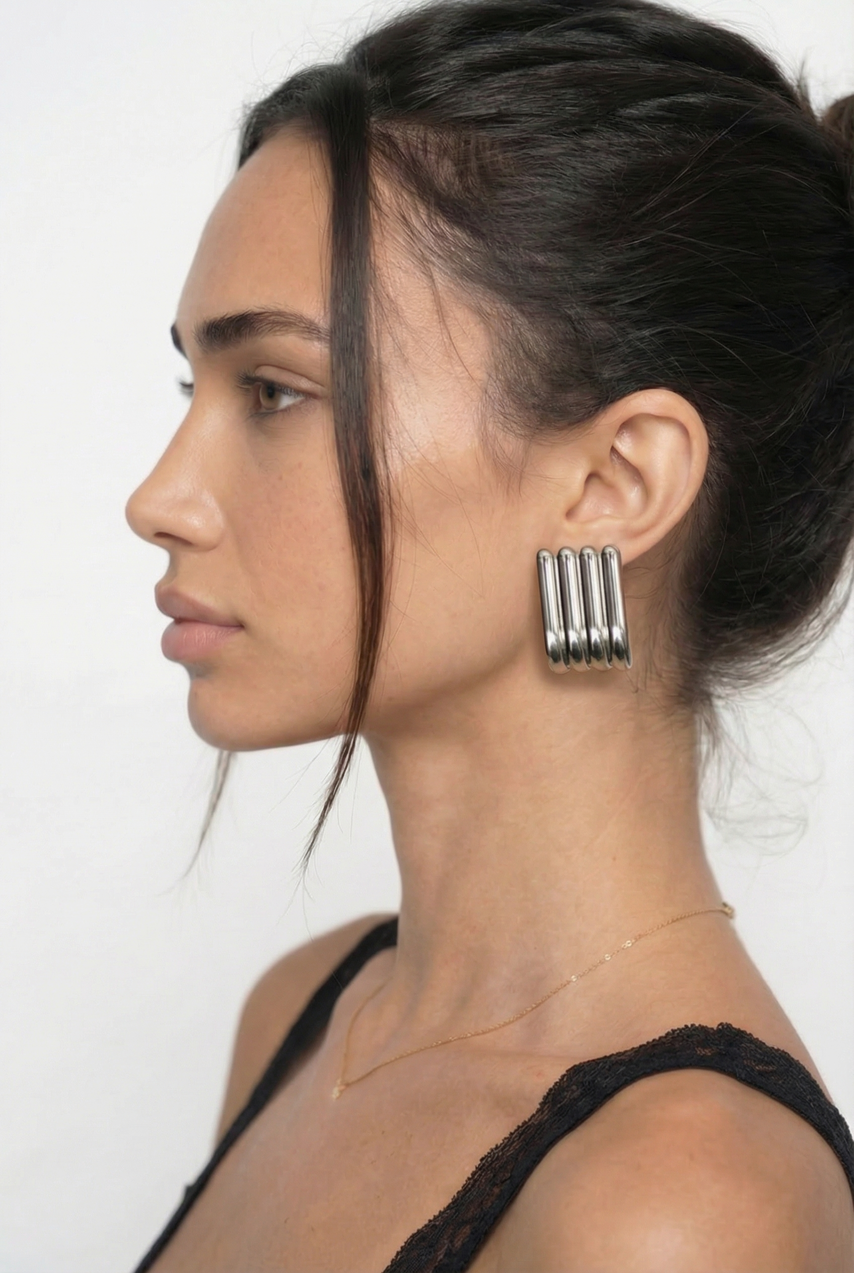 Woman wearing large hoop earrings with a plain background