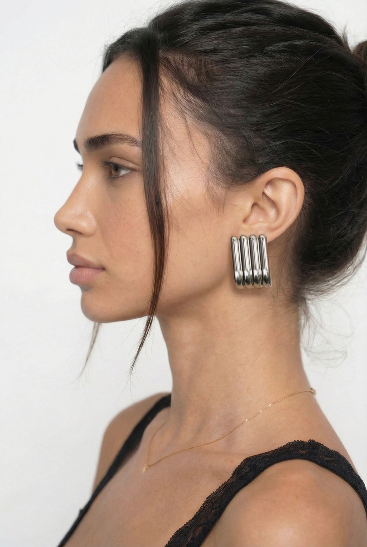 Woman wearing large hoop earrings with a plain background