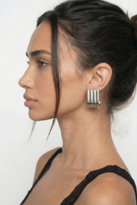 Woman wearing a silver earring with a plain background
