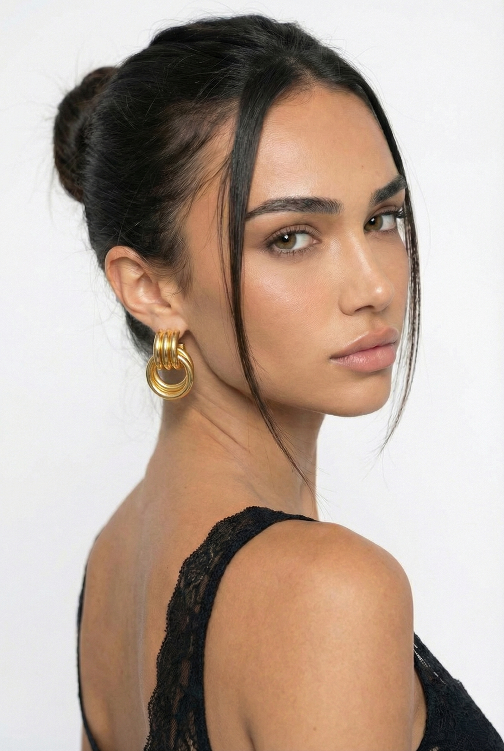 Woman with styled hair and gold earrings against a white background