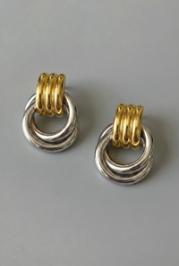 Pair of earrings with gold and silver rings on a gray background