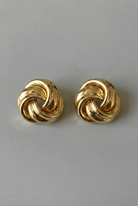 Pair of gold knot earrings on a gray background
