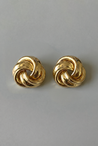 Pair of gold knot earrings on a gray background