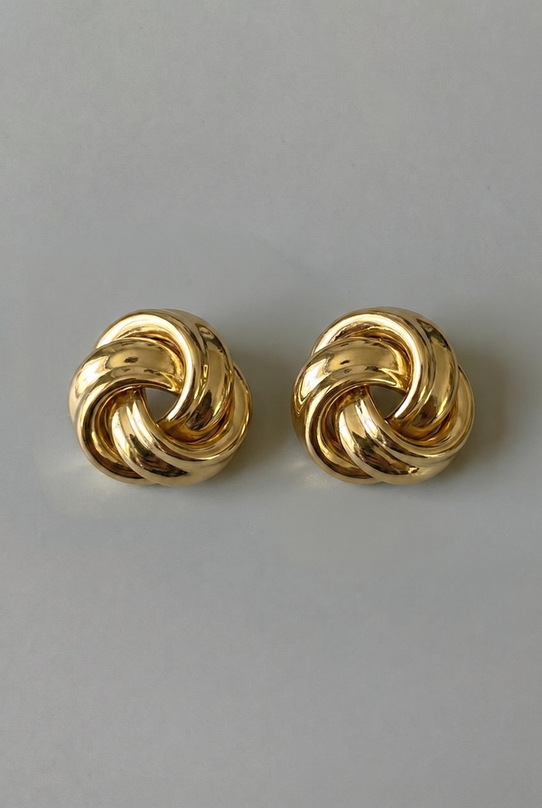 Pair of gold knot earrings on a gray background