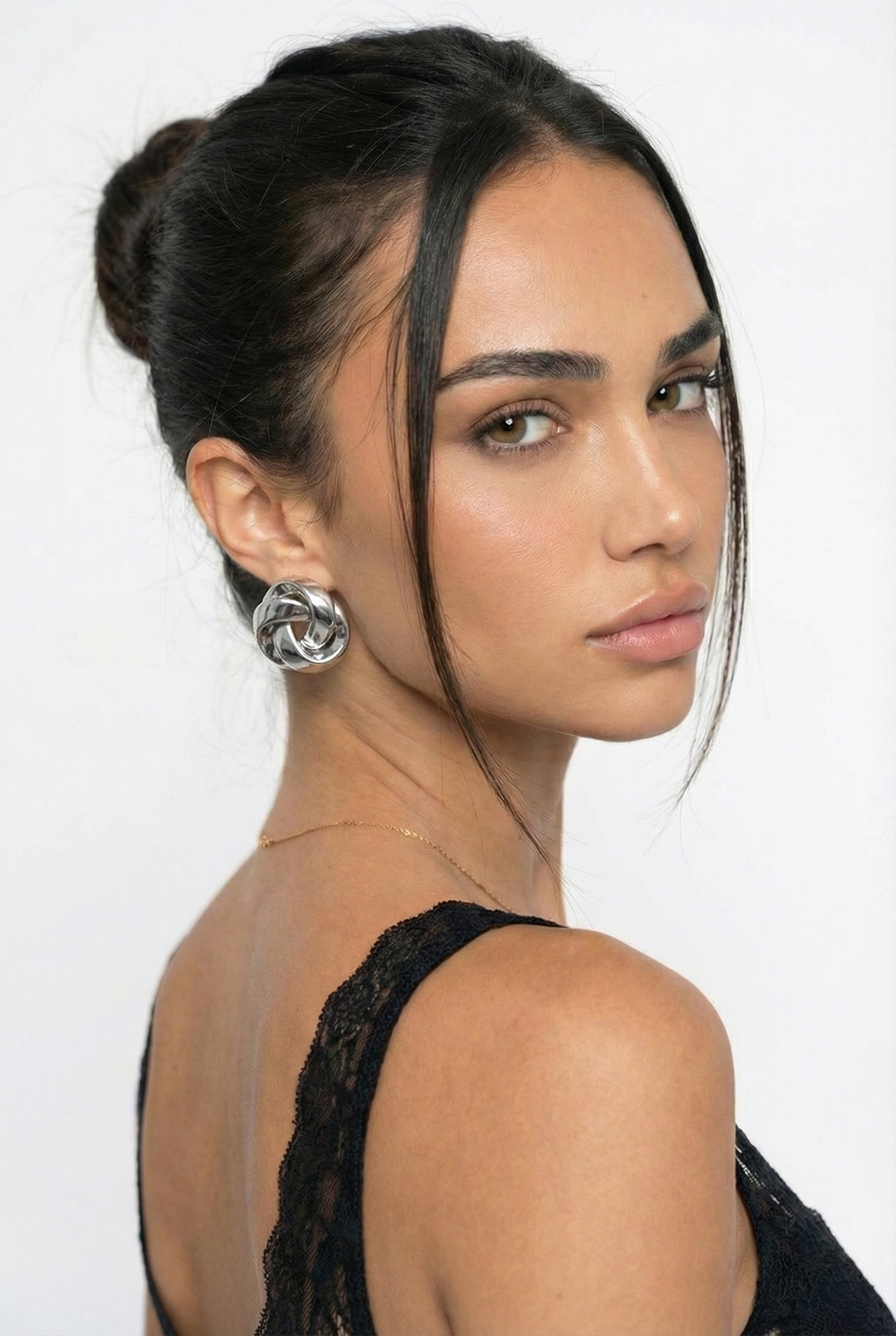 Woman with styled hair and earrings against a white background