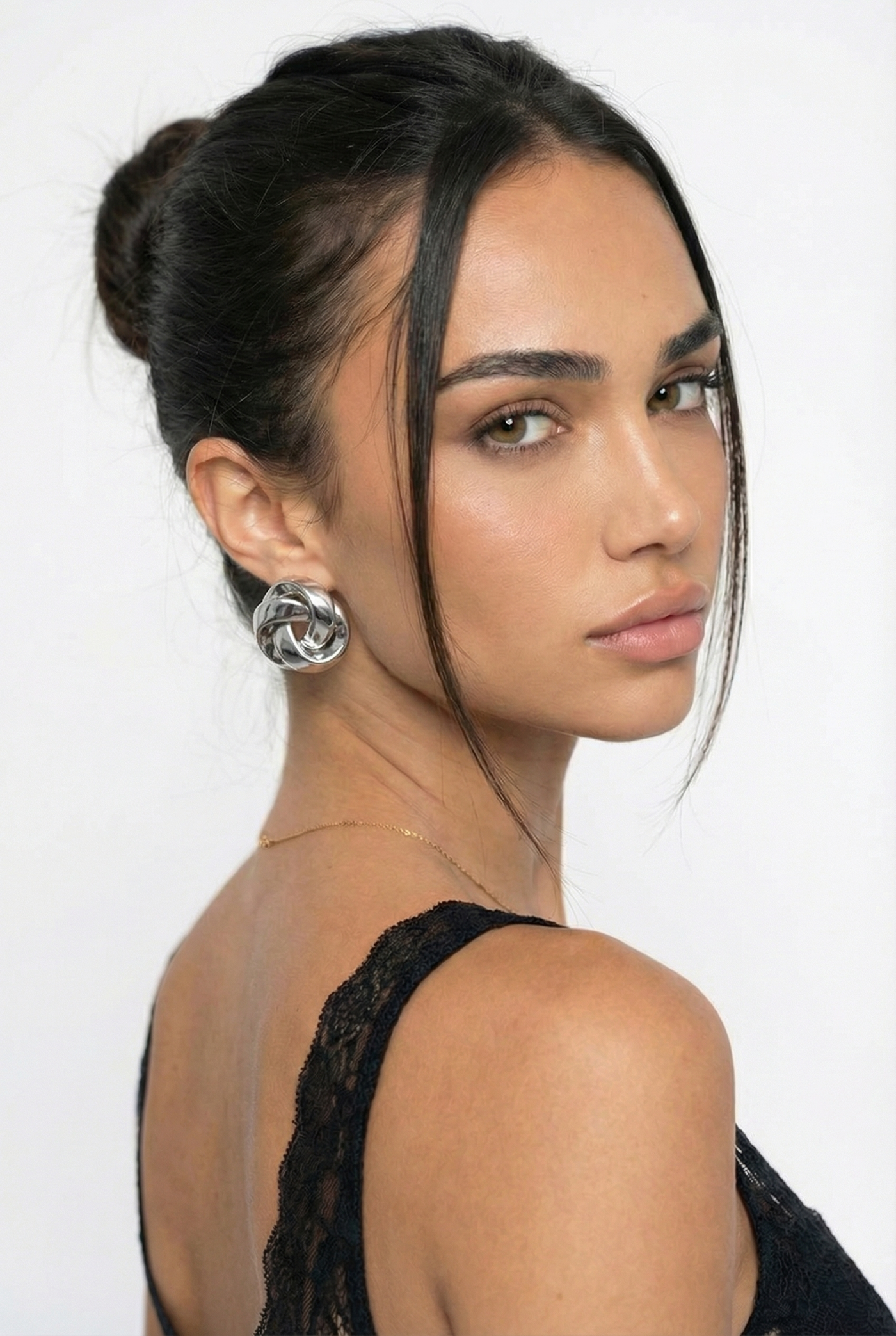 Woman with styled hair and earrings against a white background