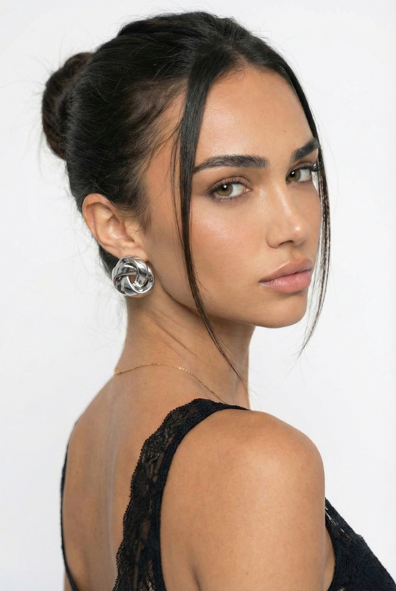 Woman with styled hair and earrings against a white background