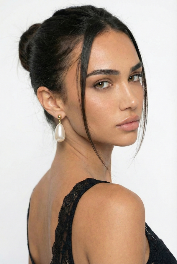 Woman with styled hair and earrings against a white background