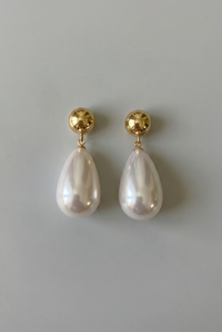 Pearl earrings with gold posts on a gray background