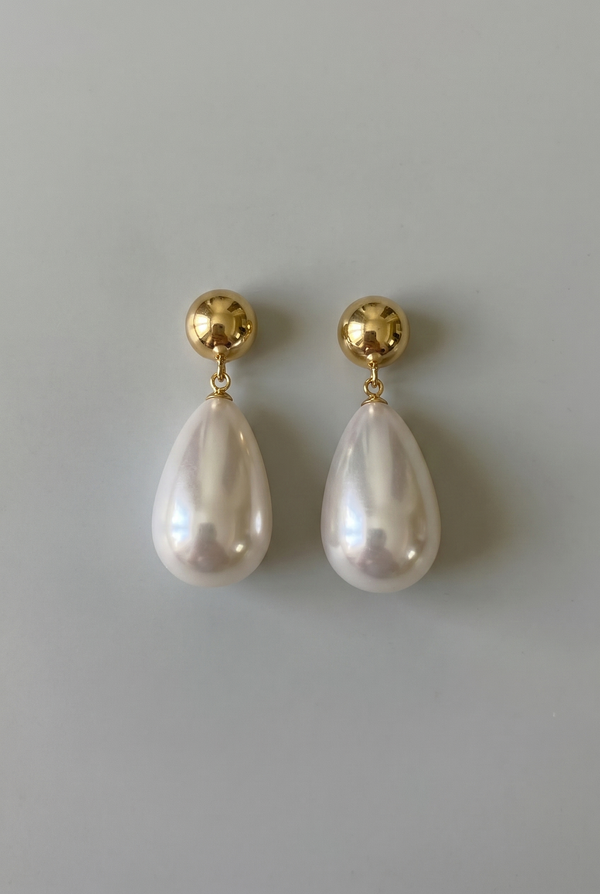 Pearl earrings with gold posts on a gray background