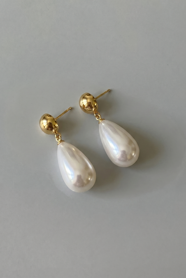 Pearl earrings with gold posts on a light gray background