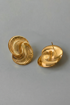 Pair of gold spiral earrings on a gray background